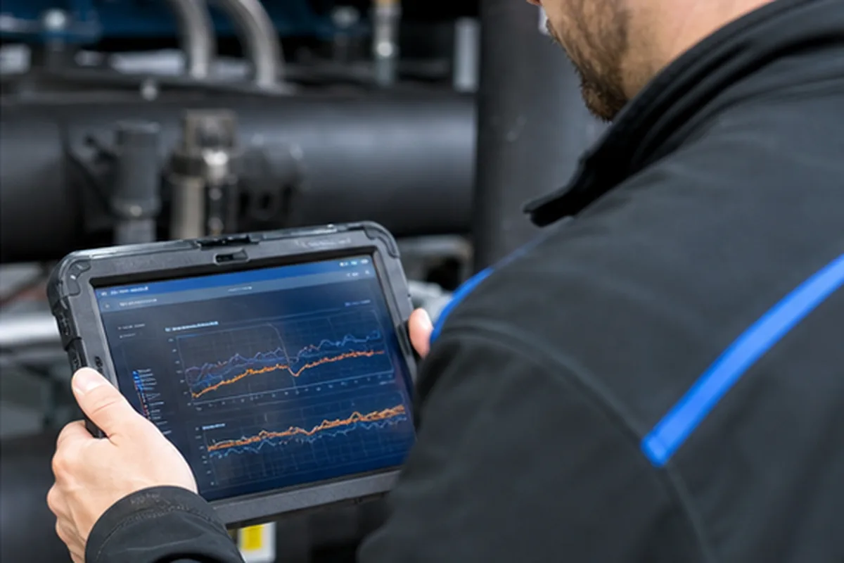 Kältetechniker analysiert Überhitzung und Ventilposition einer Industriekälteanlage auf einem Tablet