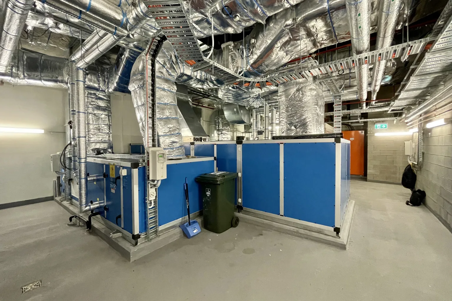 Mehrere Air-Handling-Units (Lüftungsgeräte) in einem Technikbereich eines Gewerbegebäudes; große Geräte mit angeschlossenen Luftkanälen