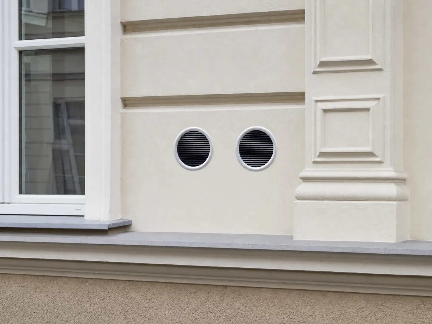 Zwei diskrete Außenwandgitter eines fest installierten Monoblock-Klimageräts an einer Wiener Fassade